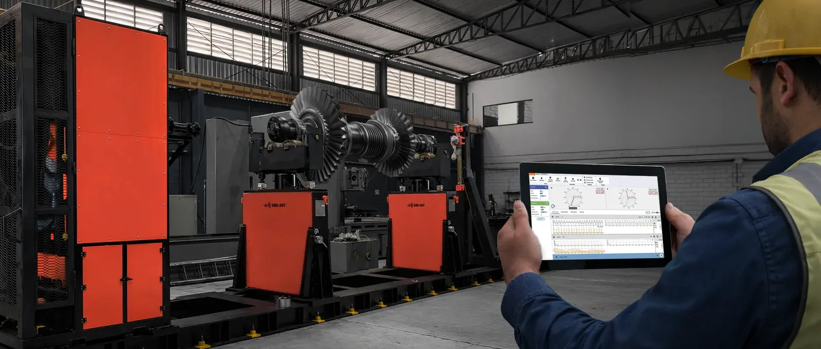 A technician holding a tablet with Digivibe MX® in front of a balancing machine with SBS-50T soft bearing supports and a turbine rotor mounted