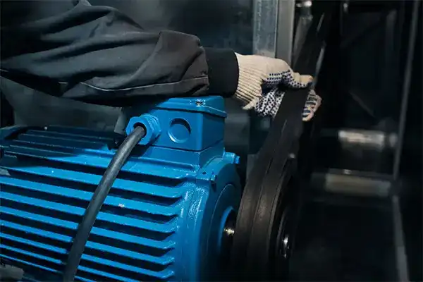 Industrial motor with belt drive system undergoing routine maintenance inspection